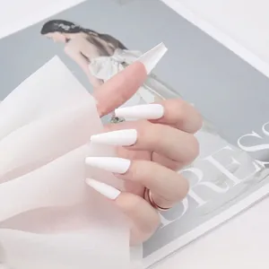 Faux ongles ballerine extra longs blanc mat portés à la main sur fond de mode élégant