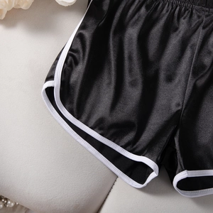Detail of satin black yoga shorts with white contrast trim and elastic waistband
