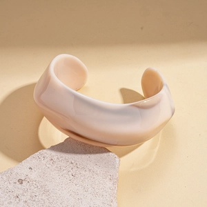 Close-up of geometric acrylic C-shaped open bangle on textured stone display