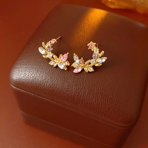 Macro view of gold vintage leaf earrings with colorful rhinestones on leather case