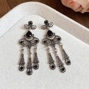 Vintage silver tassel earrings with black teardrop stones and floral carvings on fabric