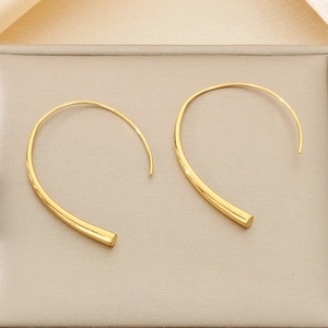 Macro detail of elegant gold curved arc earrings on premium textured display