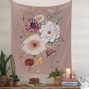 Detailed view of floral tapestry on white wall above wooden desk with green plants