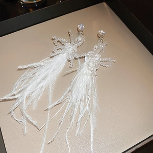 Detailed macro view of white feather tassels and crystal accents on long dangle earrings