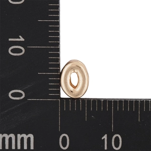 Detail showing an 8mm mini gold bubble letter charm on a metric measuring tool