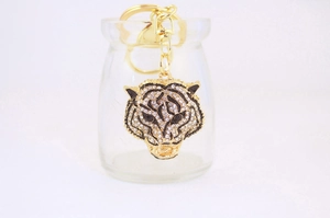 Close-up of golden tiger head keychain with sparkling rhinestones and black enamel details