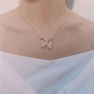 Detail of a gold butterfly necklace with pink crystal pendant on a model neck