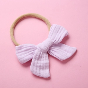 Detail of light purple muslin cotton bow headband with elastic beige nylon band for babies