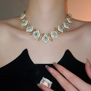 Detail of vintage gold necklace with blue enamel diamonds worn by a model