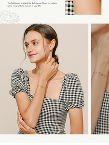 Close-up of elegant gold leaf bracelet with green zircon on woman wearing plaid dress