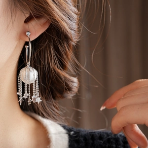 Vue détaillée des boucles d'oreilles étoiles à pompons avec perles et cage argentée
