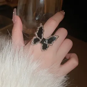 Elegant silver butterfly ring with black enamel wings worn on model hand in soft light