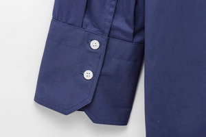 Detail of dark blue cotton shirt sleeve with double-button adjustable cuffs and white buttons