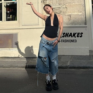 Close-up of black V-neck halter top paired with distressed oversized denim jeans