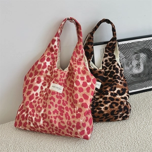 Detailed view of leopard print canvas tote bags in red and brown with brand woven label