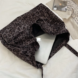 Detail view of large leopard print tote bag with laptop on a bed for daily lifestyle