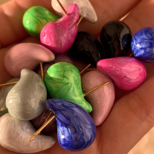 Detailed macro view of various marble-patterned resin teardrop earrings in a palm