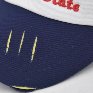 Macro detail of red 3D embroidery and vintage distressed frayed brim on cotton baseball cap