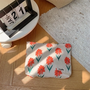 Floral cotton makeup bag with orange flower print on cream base on wooden floor