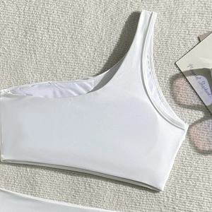 Detail of white one-shoulder bikini top with premium stitching on textured background