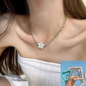 Detail of a silver bead chain necklace with a white five-petal flower diamond pendant