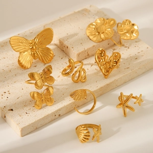 Collection of gold butterfly, snake, and heart rings displayed on a travertine stone surface
