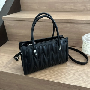 Black rectangular pleated tote bag with wavy stitching and adjustable shoulder strap