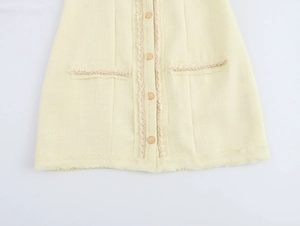 Gros plan détaillé sur le tissu en tweed jaune avec boutons dorés et bords effilochés