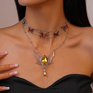 Detail of double-layer necklace with enamel butterflies and a yellow teardrop gemstone