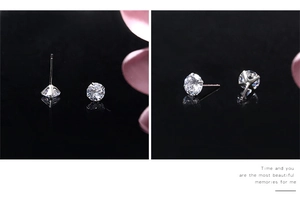 Detailed view of silver S925 sterling silver four-claw zircon stud earrings on black reflective surface