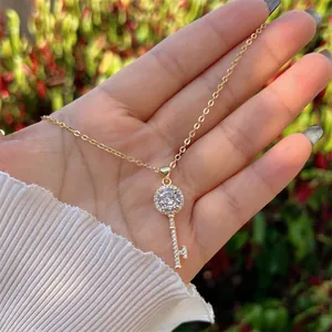 Handheld view of 18K gold plated key pendant necklace with sparkling pavé zircons