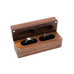 Close-up of walnut wood ring box with dual slots and soft black velvet lining
