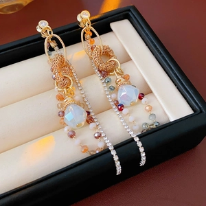 Dettaglio macro di orecchini vintage dorati con strass a goccia e nappe lunghe
