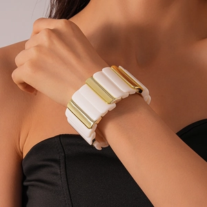 Detail of geometric acrylic and gold metal拼接 elastic bracelet on a female wrist