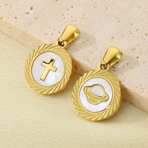 Détail de pendentifs dorés croix et planète avec nacre blanche sur fond de pierre
