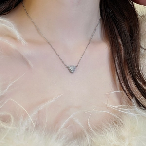 Photo de mode d'un collier triangle argenté serti de zircons porté sur tenue en plumes