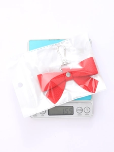 Detailed view of red leather bow keychain on scale showing lightweight 15.5g weight