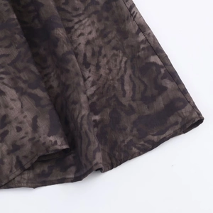 Detailed close-up of dark leopard print chiffon fabric with high-quality stitched hem