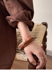 Close-up of irregular wide amber resin bangle with retro tortoiseshell texture and gloss