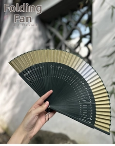 Deep green Chinese folding fan with hollowed bamboo ribs and elegant gold gradient edge