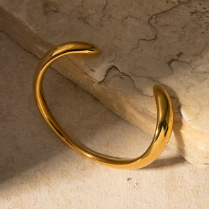 Elegant 18k gold plated stainless steel irregular open bangle on natural rock background
