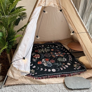 Bohemian moon phase woven throw blanket with floral pattern and red tassels on floor