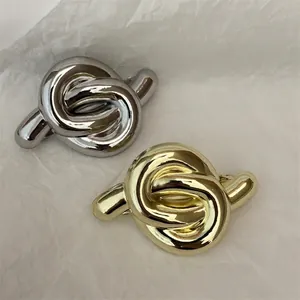 Knot design metal hair clips in gold and silver finish on a white textured background