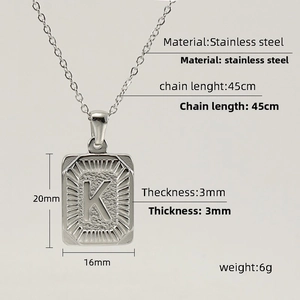 Macro shot of silver stainless steel square pendant with letter K and sunburst texture