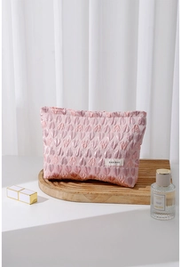 Close-up of pink heart jacquard canvas makeup bag with H&R BAG logo on a wooden tray