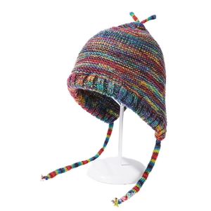 Close-up of rainbow striped knit earflap hat with colorful textured yarn and pompom ties