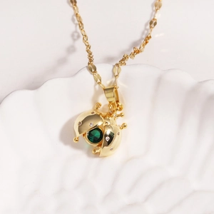 Macro shot of opening red enamel ladybug pendant revealing hidden green gemstone jewelry