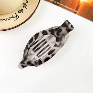 Detail view of oval leopard print acetate hair claw clip on minimalist white background