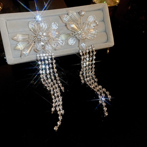 Macro view of crystal flower earrings with long rhinestone tassels on velvet tray