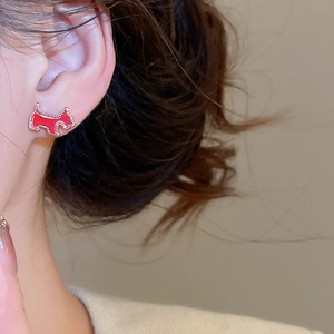 Close-up of red dog stud earring with gold-plated trim on model's ear